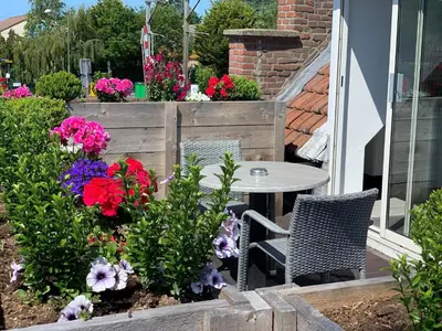 a patio with a table and chairs and flowers at Slapen bij de Buurvrouw in Castricum