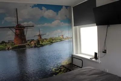 a bedroom with a window with a painting of windmills at Slapen bij de Buurvrouw in Castricum
