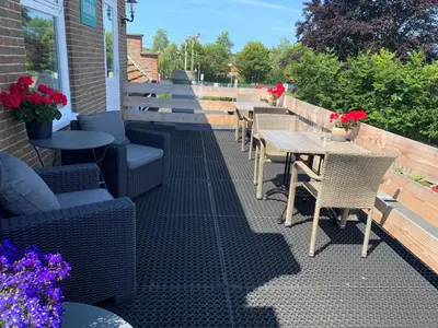 an outdoor patio with tables and chairs and flowers at Slapen bij de Buurvrouw in Castricum
