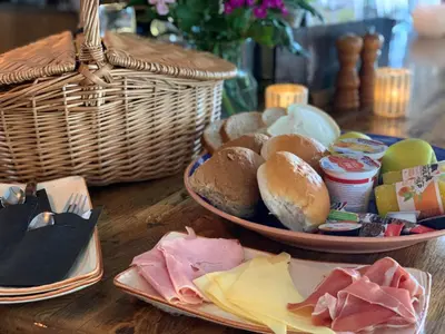 a table with a plate of bread and a basket of food at Slapen bij de Buurvrouw in Castricum