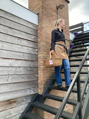 a woman standing on some stairs with a basket at Slapen bij de Buurvrouw in Castricum