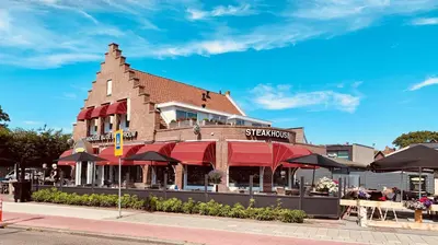 a building with a restaurant with umbrellas on a street at Slapen bij de Buurvrouw in Castricum