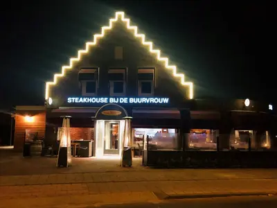 a building with a sign for a store at night at Slapen bij de Buurvrouw in Castricum