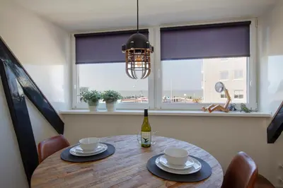 a dining room table with a bottle of wine and a window at Seapoint - Sea view in Zandvoort
