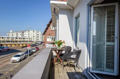 a balcony with a table and a view of a street at Seapoint - Sea view in Zandvoort