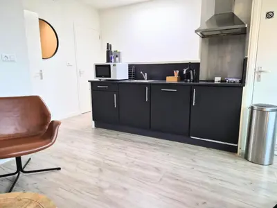 a kitchen with black cabinets and a microwave at Seapoint - Sea view in Zandvoort