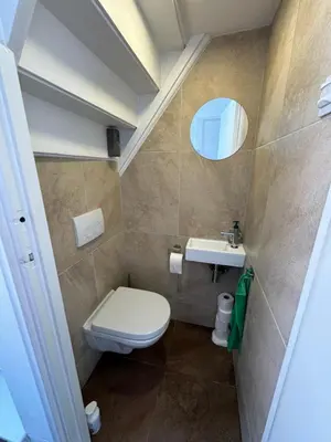 a bathroom with a toilet and a sink and a mirror at Maisonnette Indysenne in Zandvoort