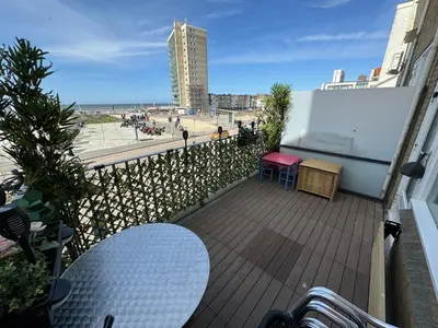 a balcony with a table and a view of the beach at Maisonnette Indysenne in Zandvoort