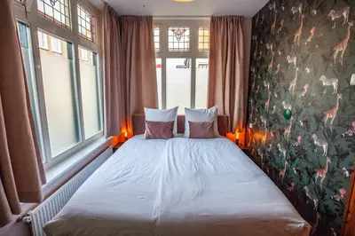 a bedroom with a bed with two pillows and two windows at Oosterhouse in Zandvoort