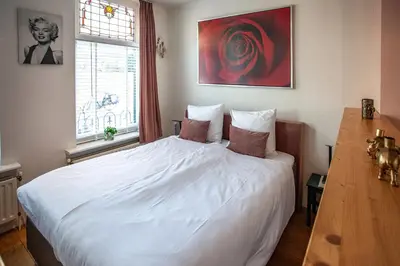 a bedroom with a white bed and a large window at Oosterhouse in Zandvoort