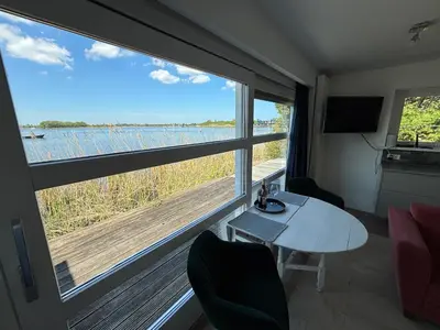 a room with a table and chairs and a large window at Vakantiehuis aan De Mooie Nel in Spaarndam