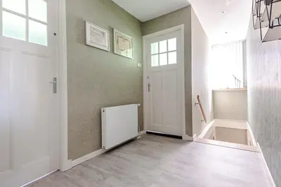 a hallway with a white door and a staircase at Family Home Hendriks in Zandvoort