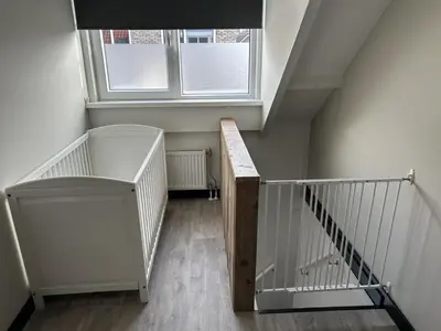 a staircase with a wooden railing and a window at Sonnblick in Egmond aan Zee