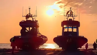 two large boats sitting on the beach at sunset at Sonnblick in Egmond aan Zee