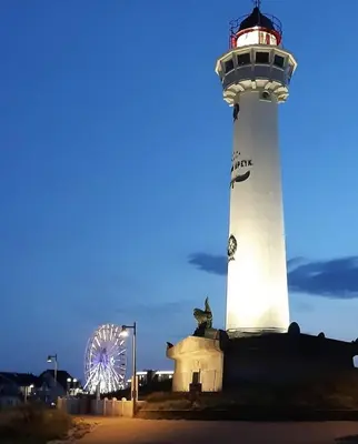 a lighthouse with a ferris wheel in front of it at Sonnblick in Egmond aan Zee