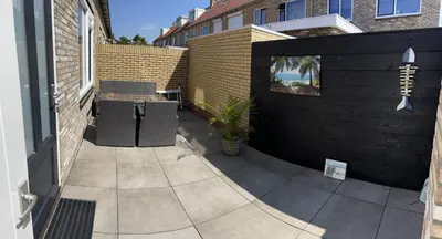a patio with two chairs and a table and a fence at Sonnblick in Egmond aan Zee