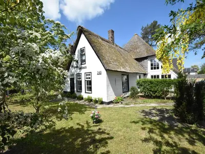 a white house with a shingled roof at Luxuriously restored farmhouse with trendy interior close to sea and forest in Groet