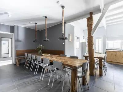 a dining room with a wooden table and chairs at Luxuriously restored farmhouse with trendy interior close to sea and forest in Groet
