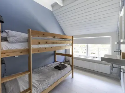 a bedroom with bunk beds in a room with a window at Luxuriously restored farmhouse with trendy interior close to sea and forest in Groet