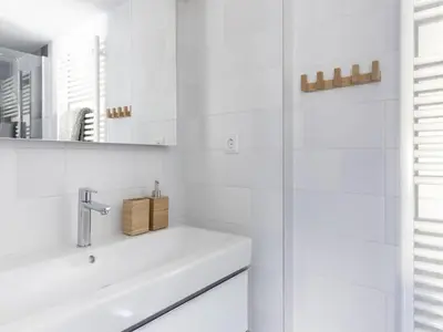 a white bathroom with a sink and a mirror at Luxuriously restored farmhouse with trendy interior close to sea and forest in Groet