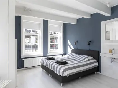 a bedroom with a bed with blue walls and windows at Luxuriously restored farmhouse with trendy interior close to sea and forest in Groet