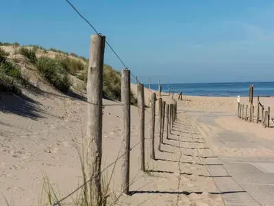a fence on the beach next to the ocean at Holiday Home in Noordwijk near the Beach in Noordwijk
