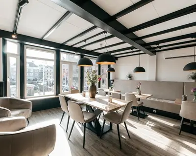 a dining room with a table and chairs and windows at Hotel van Gelder in Amsterdam