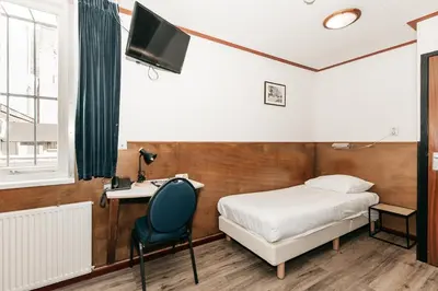 a bedroom with a bed and a desk and a tv at Hotel van Gelder in Amsterdam