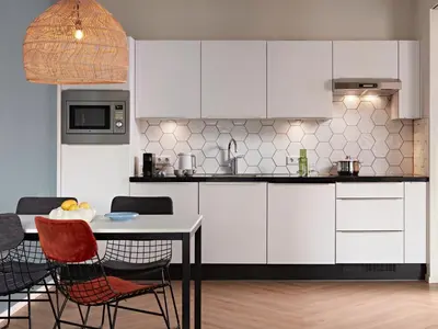 a kitchen with white cabinets and a table and chairs at Numa Amsterdam Docklands in Amsterdam