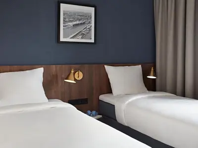 two beds in a hotel room with white sheets at Numa Amsterdam Docklands in Amsterdam