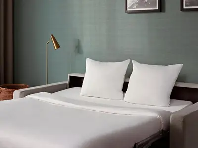 a bed with white sheets and pillows in a room at Numa Amsterdam Docklands in Amsterdam
