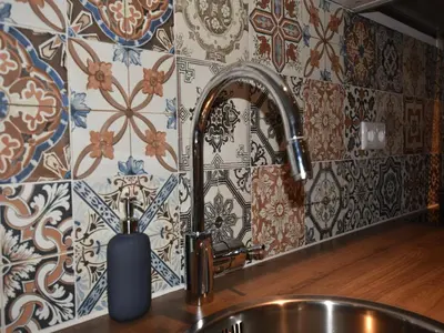 a kitchen sink with a faucet and a tile wall at Holiday Home in Egmond by the Beach in Egmond aan Zee