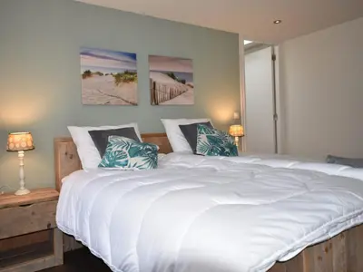a bedroom with a large white bed with blue pillows at Holiday Home in Egmond by the Beach in Egmond aan Zee