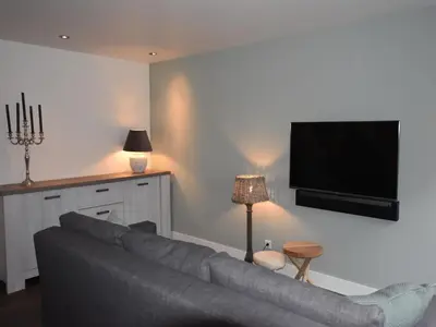a living room with a couch and a flat screen tv at Holiday Home in Egmond by the Beach in Egmond aan Zee