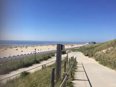 a sandy beach with people on the beach at De Nollen in Egmond aan den Hoef