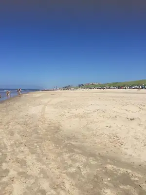a group of people walking on a sandy beach at De Nollen in Egmond aan den Hoef