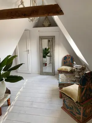 an attic hallway with a mirror and a chair at Casa Blanca Old City - Alkmaar in Alkmaar