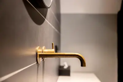 a brass faucet on a wall in a bathroom at CTY Books in Leiden