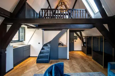 an attic kitchen with a staircase and blue chairs at CTY Books in Leiden