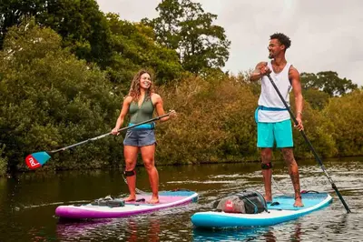 a man and a woman on paddle boards in the water at Cozy tiny house close to Schiphol Ams Airport in Rijsenhout