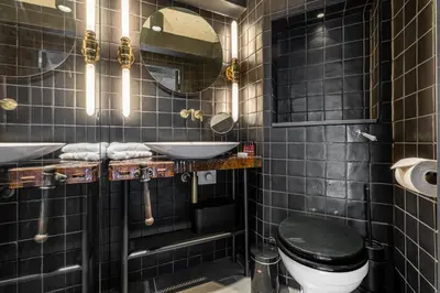 a black tiled bathroom with a toilet and a sink at Boutique Hotel The Craftsmen in Amsterdam