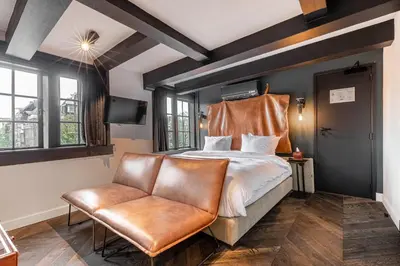 a bedroom with a bed and a leather chair at Boutique Hotel The Craftsmen in Amsterdam