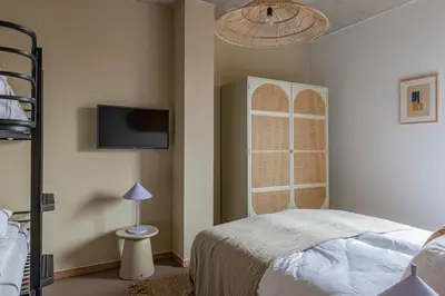 a bedroom with a bed and a tv on the wall at Strandhotel Zoomers in Castricum