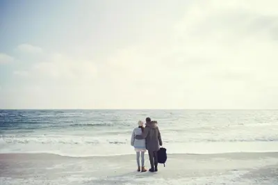 two people standing on the beach looking at the ocean at Strandhotel Zoomers in Castricum