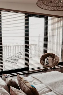 a bedroom with a bed and a chair and large windows at Strandhotel Zoomers in Castricum