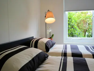 two beds in a bedroom with a window at Charming Garden Retreat in Noordwijkerhout