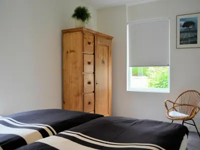 a bedroom with a bed and a dresser and a window at Charming Garden Retreat in Noordwijkerhout