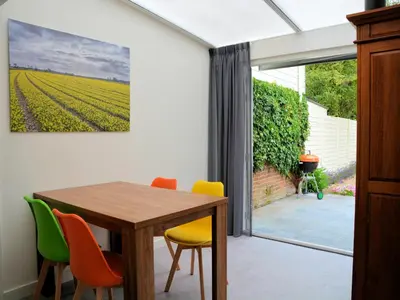 a dining room with a table and chairs and a window at Charming Garden Retreat in Noordwijkerhout