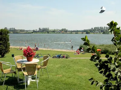 a table with chairs and people in the water at Charming Garden Retreat in Noordwijkerhout