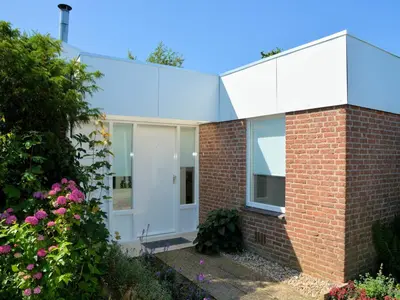 a brick house with white doors and a brick wall at Charming Garden Retreat in Noordwijkerhout